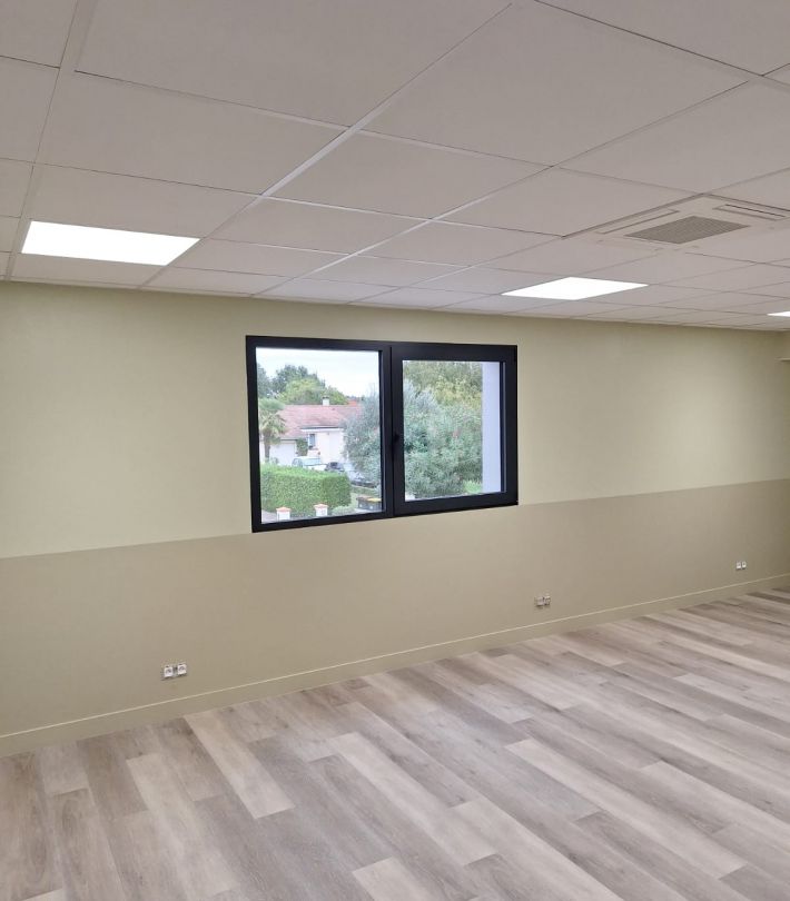 Artisan peignant un mur de salon en deux couleurs à Blagnac